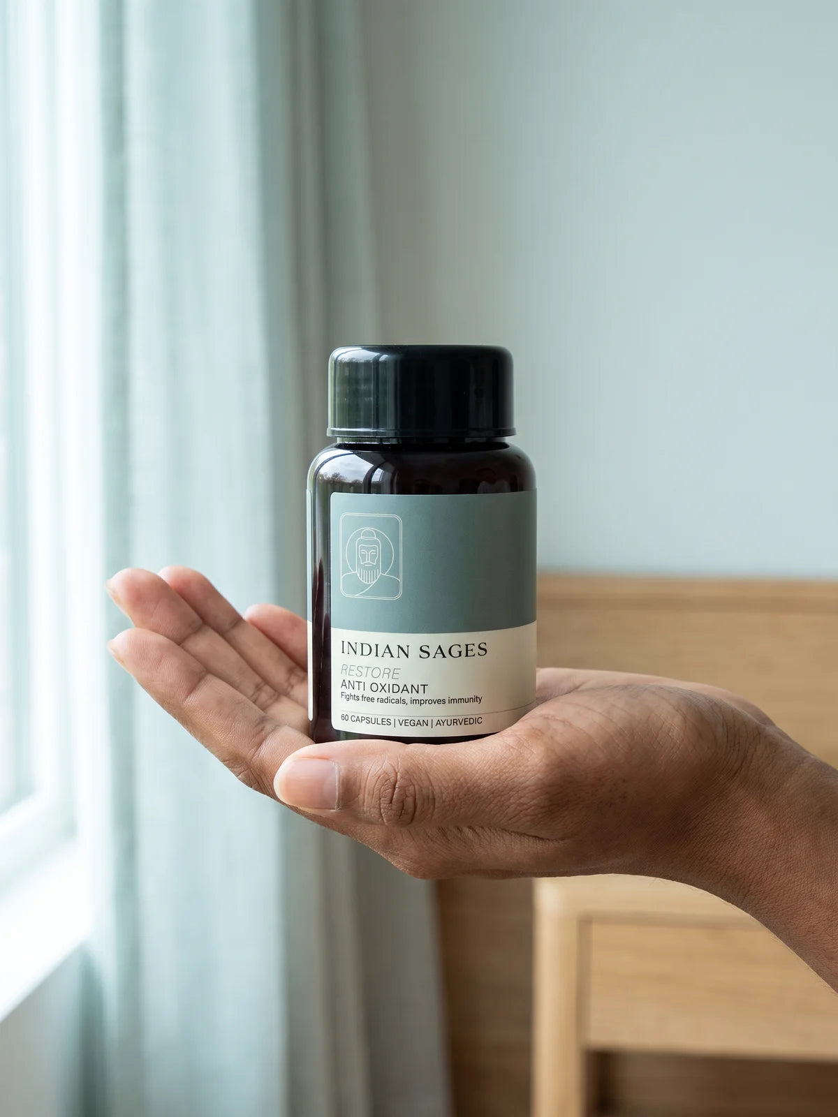 A hand holding a bottle of RESTORE in soft morning light.