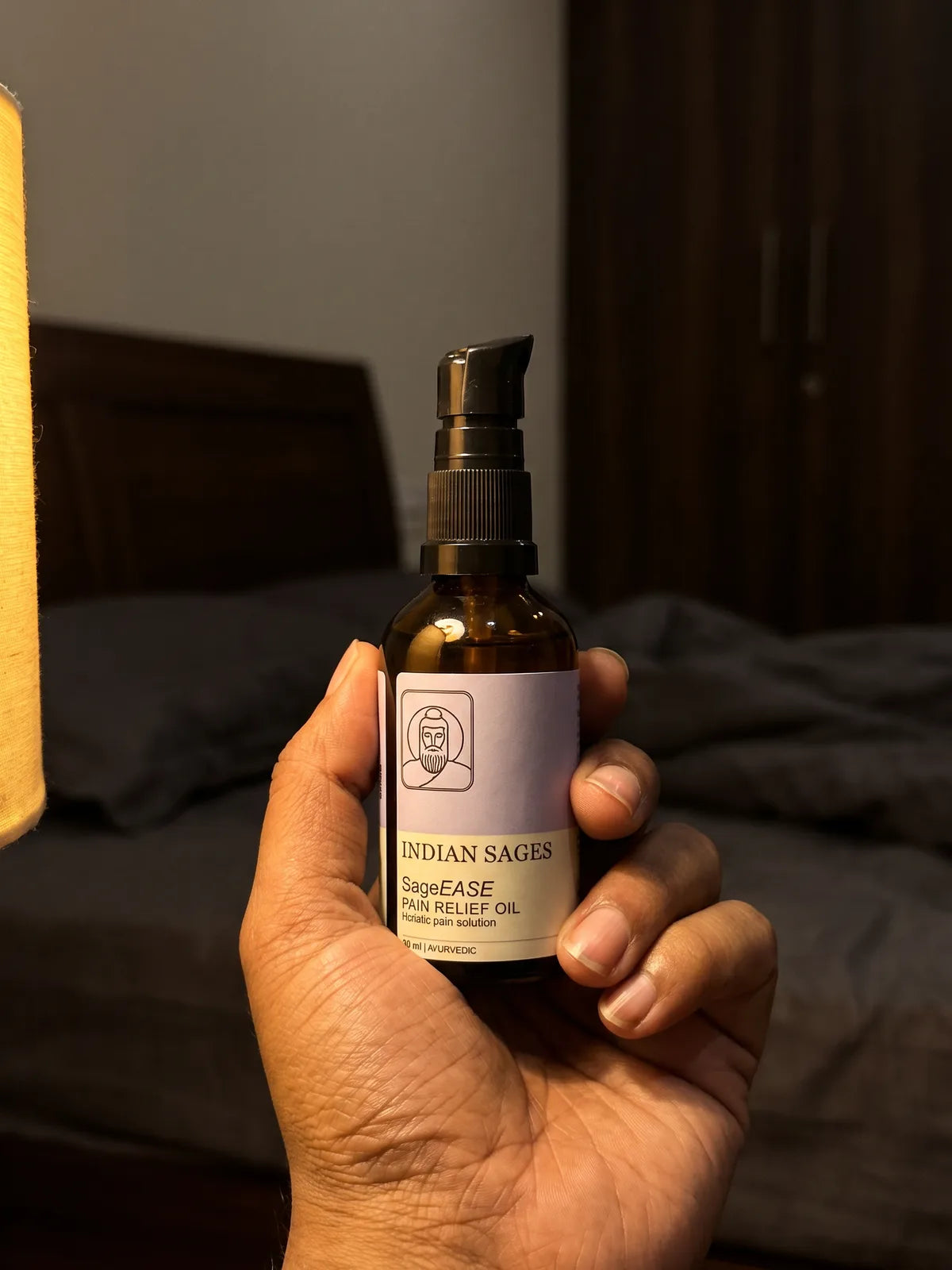 A hand holding a bottle of SageEASE in warm evening light.